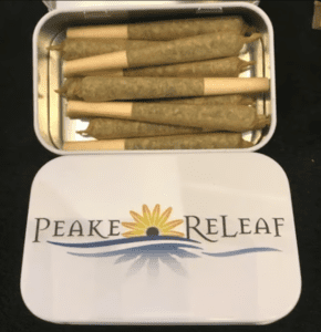 An open Peake ReLeaf tin containing ten Dreadbread pre-rolls, neatly arranged inside a metallic case with the Peake ReLeaf logo on the lid.