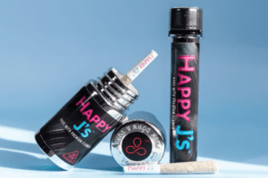 Happy J’s cannabis pre-rolls displayed with a black and neon-branded tube, tin, and joint, set against a bright blue background.